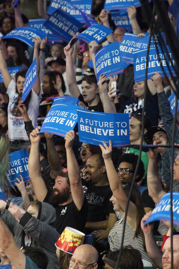 The crowd behind Sanders holds up the official campaign signs. The signs say “A future to believe in” which is Sanders’ campaign slogan.
