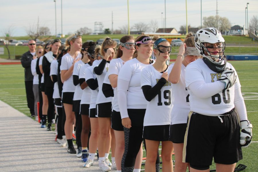 The varsity girls lacrosse team lines up for the national anthem ahead of their game with Incarnate Word Academy on 4/21.