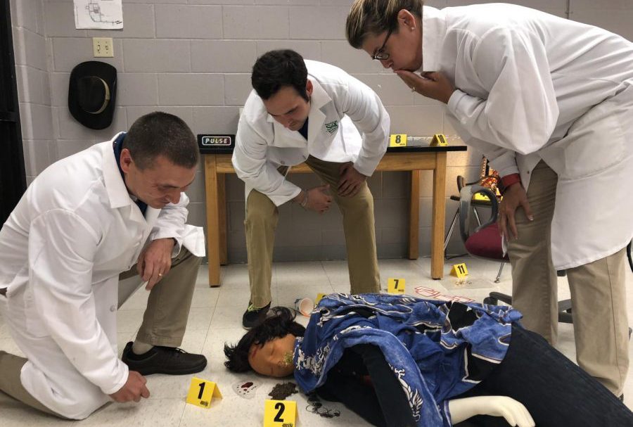 (From left) Chris Dalton, Matt Howard and Dawn Hahn investigate the crime scene of Anna Garcia, a person of study in Principals of Biomedical Science. All three teachers have taken on new PLTW classes this year.