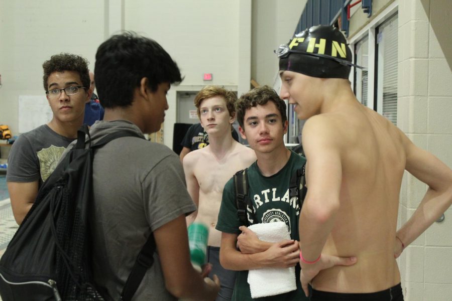 Freshman Stan Lindquist [dark green shirt] talks with his teammates during a swim meet