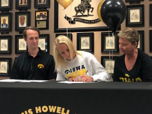 Senior Sam Cary signs a paper to commit to the University of Iowa.