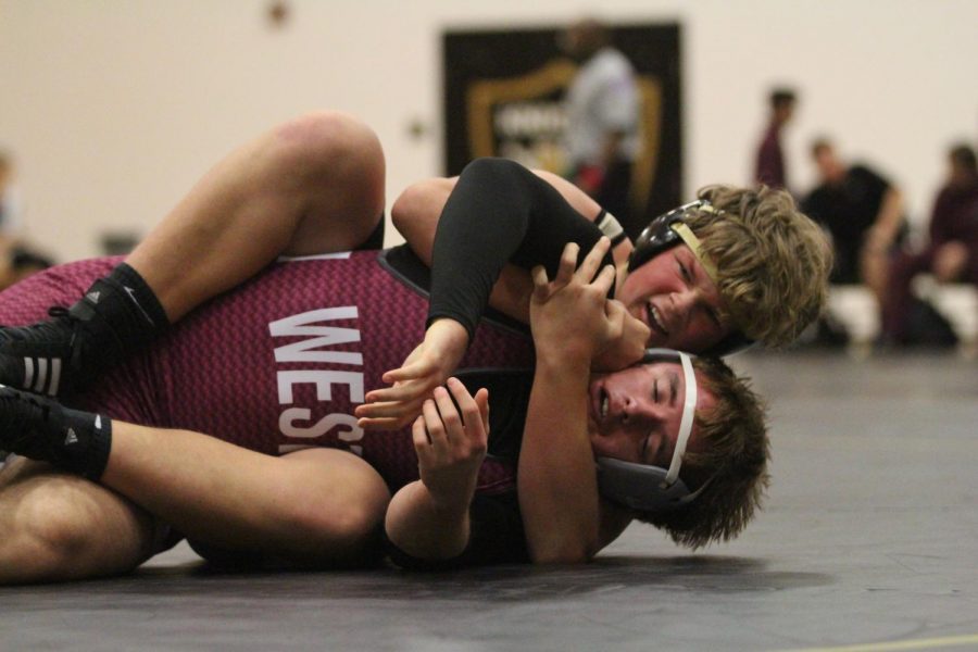 Sophomore Jesse Collins holds down a St. Charles West wrestler in an attempt to pin him.