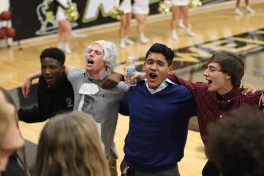 Seniors Josh Simmons, Dillon Lauer, Noe Bustos and Adam Shine link arms and sway side to side to get the crowd to cheer along with them during the first girls’ varsity basketball game on Dec. 7. The Goonies began holding meetings this year to help increase attendance and spirit at winter sports games.