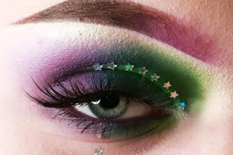 18-year-old Evelyn Moeckel models her Mardi Gras eye makeup. Moeckel is a self-taught makeup artist who specializes in eye makeup. She works at Sephora Beauty which requires her to do fun makeup to inspire her clientele. Moeckel strives to go above and beyond with new designs.