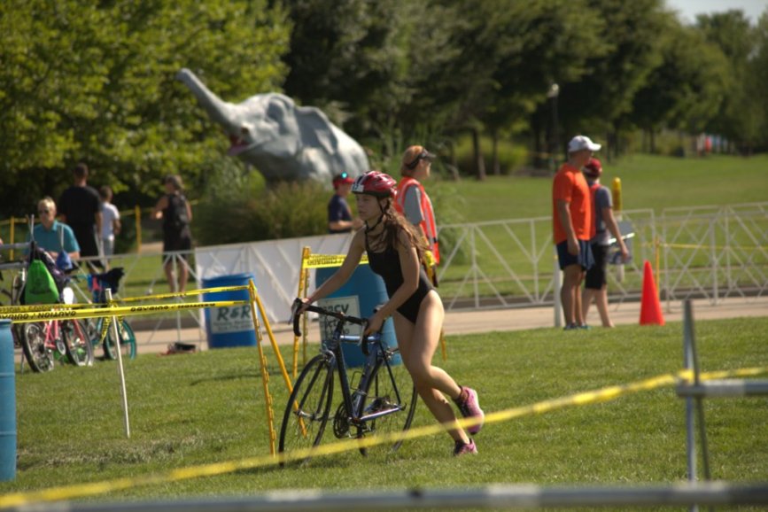 Sophomore Olivia Neunaber runs with her bike to gain momentum during her triathlon.
