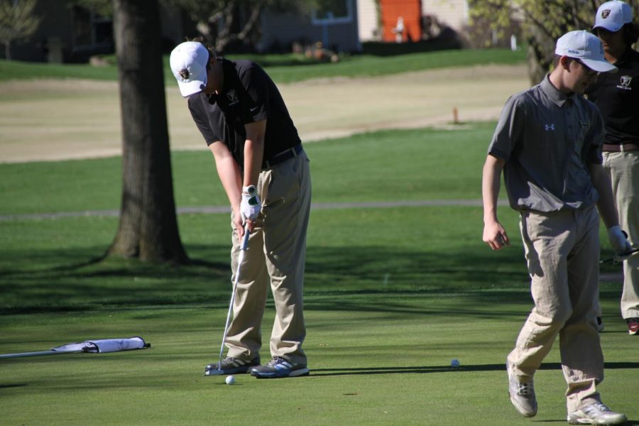 A Knight golfer putts a ball on the green in a competition.