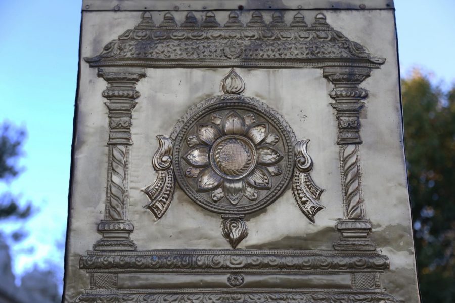 A sudarshana chakra pressed into brass rests on the pillar standing outside the temple. The symbol, whose name translates to disk of auspicious vision in Sanskrit, is associated with Lord Vishnu. Lord Vishnu, who acts as the preserver of the universe in Hindu religion, utilizes the chakram (which translates to disk/discus) as his weapon. 