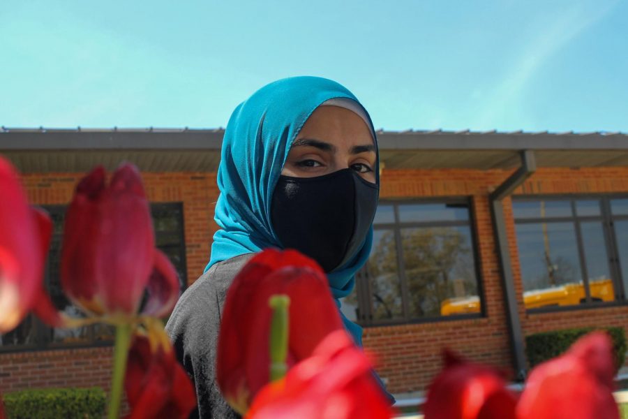 Senior Shahed Abdallah poses in front of the school with her mask on.