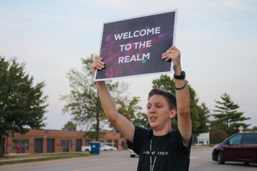 Jonah Sevier holds a sign welcoming students to The Realm on Sept. 9. Sevier is a part of the welcome team at the JuniorRealm, which is a youth group center for Waypoint church.