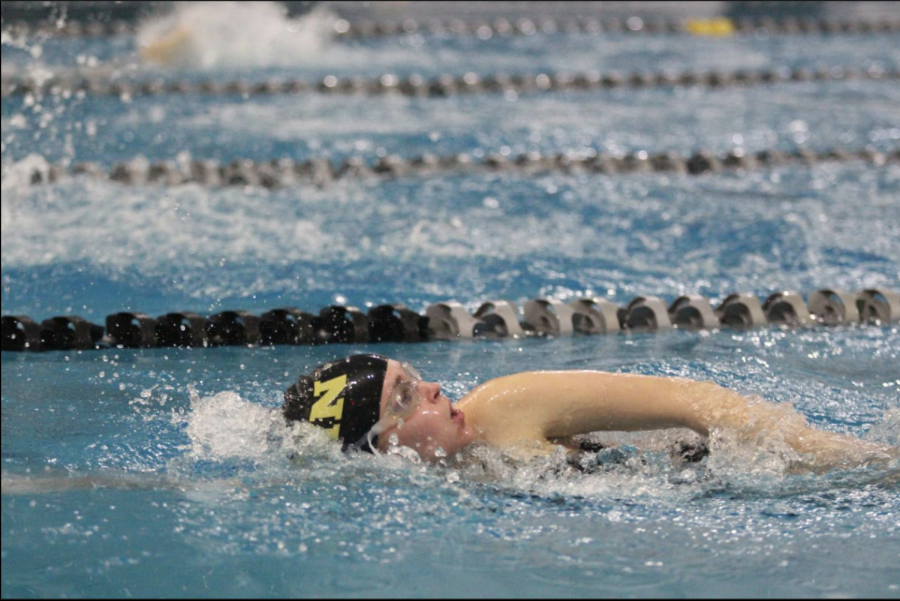 a swimmer from the 2020-21 team competes in a meet 