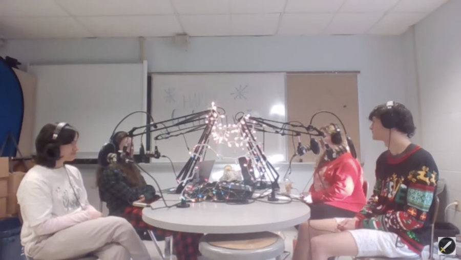 Members of the podcast team sit around a table during the live 12 hour podcast