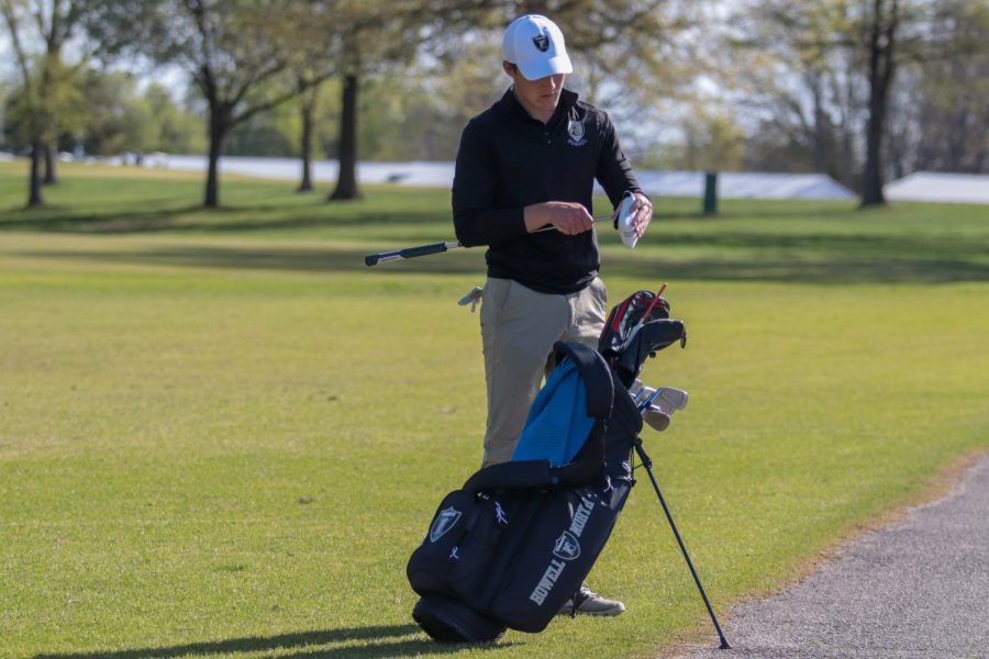 Senior Joey Key cleans his golf clubs in between holes at the Warrenton Invitational on April 14, 2021