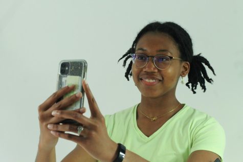 Senior Nila Milo poses with her phone as if about to post a photo for social media. Milo has recently deleted all of her social media accounts