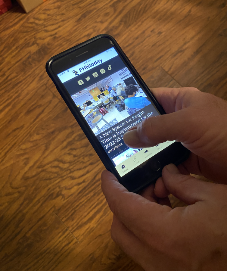 A person holds an Iphone with the FHNtoday app open on the screen