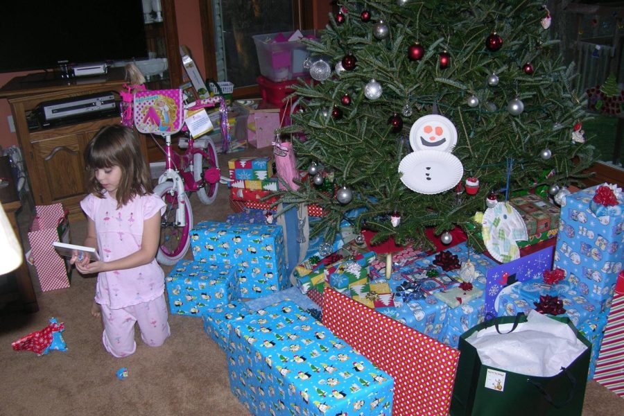 A 6 year old McKenna Hudson sits under the tree and unwraps her Christmas presents in 2011.