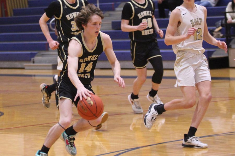 Senior Brandon Reale dribbles a basketball in a game against Holt. 