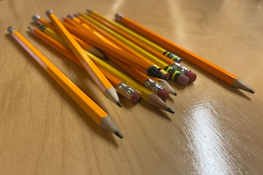 Pencils sit grouped together on a table. 