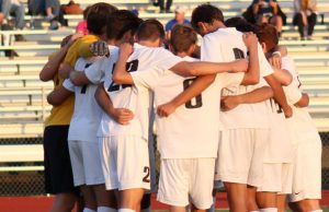 The varsity boys soccer starting 11 huddle before a match against FHHS on Oct. 11 (file photo)
