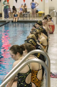 The Girls' Swimming team watches their teammate during a meet.