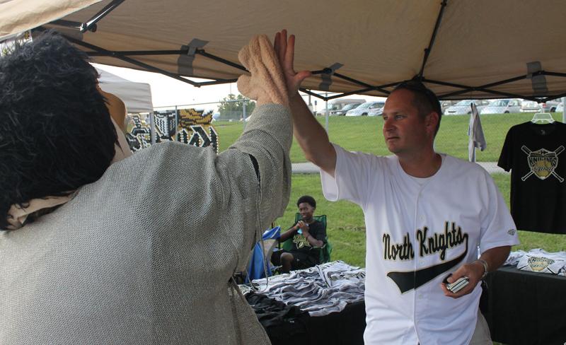 Norm high fives Mr. Janes  while he was helping sell FHN apparel at the softball booth. The softball players were also walking around the event selling lemonade. Throughout the day, Norm visited all of the booths and gave many high fives.