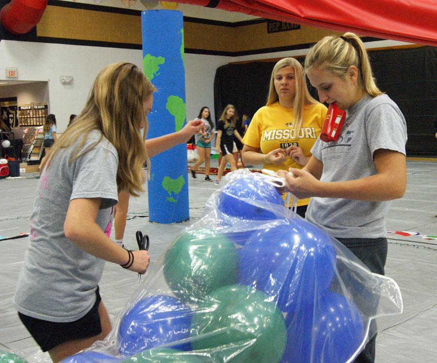 Nicole Morse, holding her french fries in her mouth, helps tie the balloon bags up to the curtain in the big gym. This years Homcoming dance decorations were set up by our proud student councel with this years theme of "Around the World." To obey this theme there were different well known symbols of popular locations such as chinese dragons, the eiffel tower, the beach, and the rainforest.