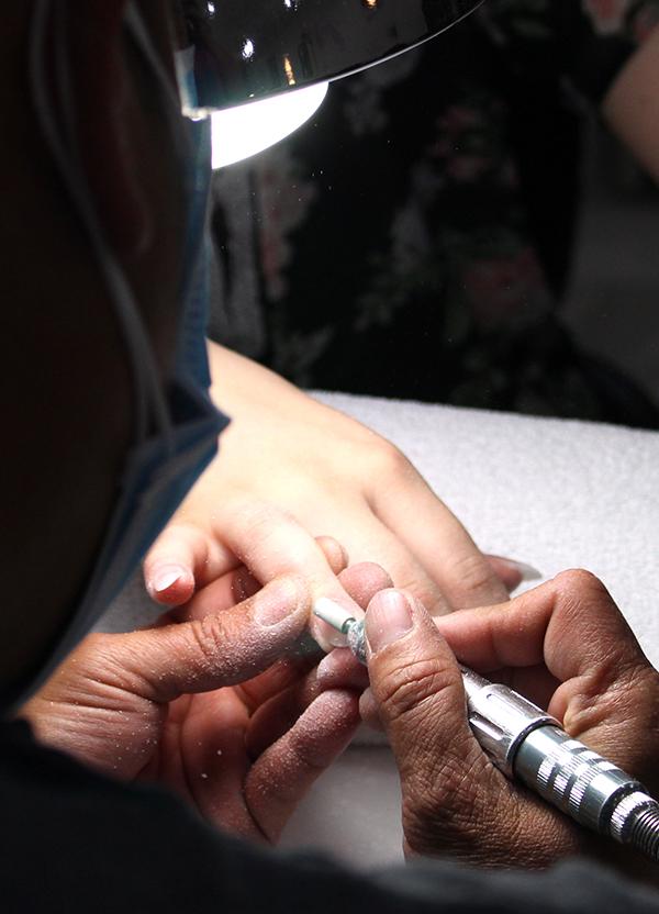 The nail artist starts to sand down the acrylic. They have to sand the nails down to help shape them and also to make the nails thinner. If they don't sand them down the nails would be very thick and wouldn't look real. 