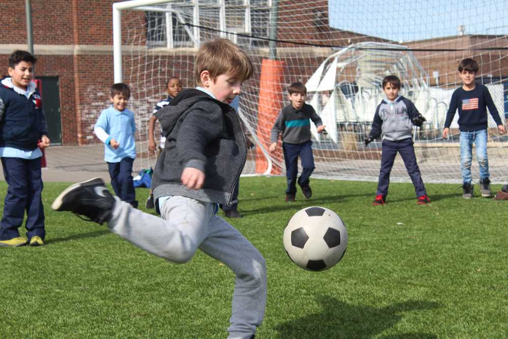 A student plays soccer with his classmates during recess outside of the Nahed Chapman American Academy. The soccer field the students play on was funded by donors to the school in support of a turf field.