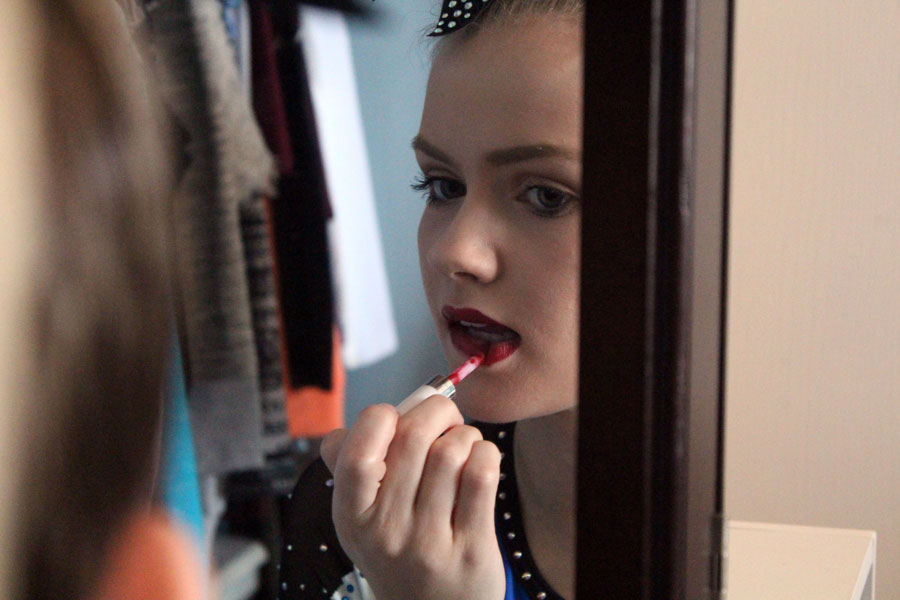 Jensen puts on lip gloss as she gets ready for her competition. Some gyms have rules on what makeup their cheerleaders wear. At Jensen's current gym, Cheer St. Louis, they want the makeup to look natural. 