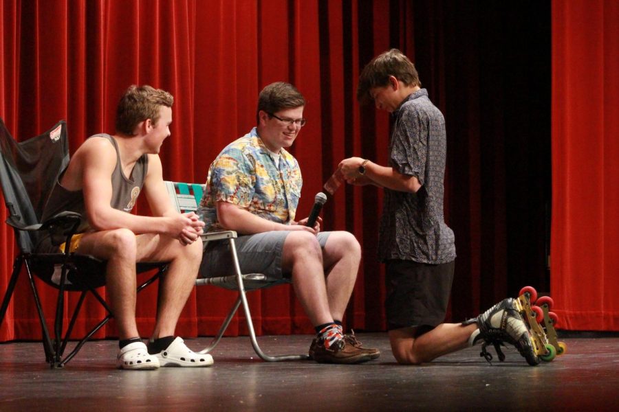 Senior Trevor Bohnert gets the waxing strip ready to use on senior Christopher St. Aubin's leg as senior Drew Lanig watches. St. Aubin's talent portion included having Bohnert wax his legs along with Lanig. This event ended with having to hold Lanig down in the chair to wax his legs.