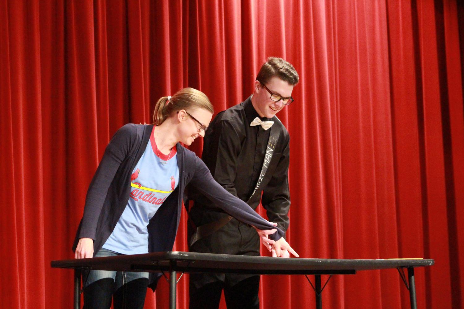 Senior Sean Rhomberg, Mr. Magic Man, shows english teacher, Kristen Johnson, and crowd part of his magic trick. Rhomberg`s first magic trick included playing cards and magically finding Johnson's card through the shuffled deck. He then moved on to show the crowd another magic trick that included knowing a total of numbers before the audience even knew what the numbers were going to be. 