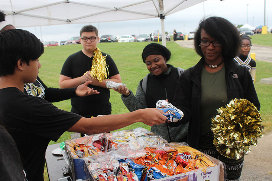 A Student Council member hands chips to students during the Homecoming Tailgate. 