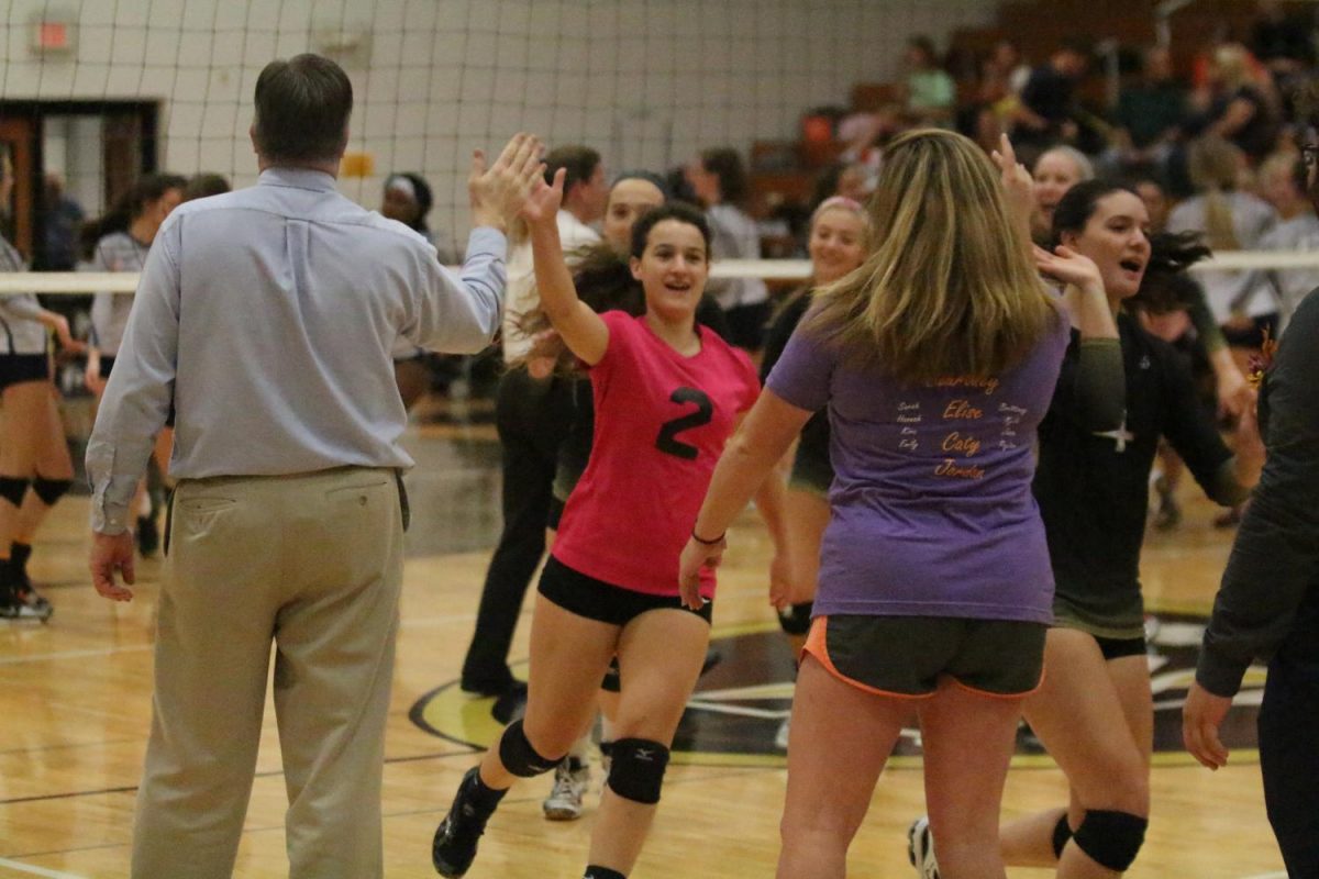 Junior Sarah Zimmerman high fives her coach and teammates before the match.