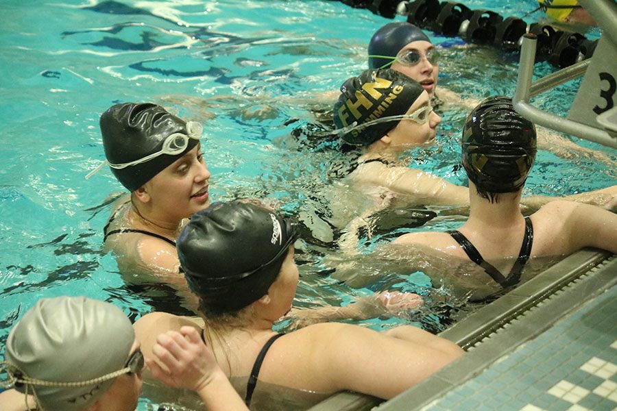 The Howell North Lady Knights girls swimming team huddles in the swimming pool