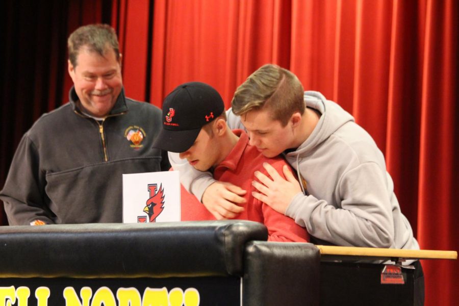 Connor Gallagher signs for William Jewell College with his brother Evan watching over his shoulder. 