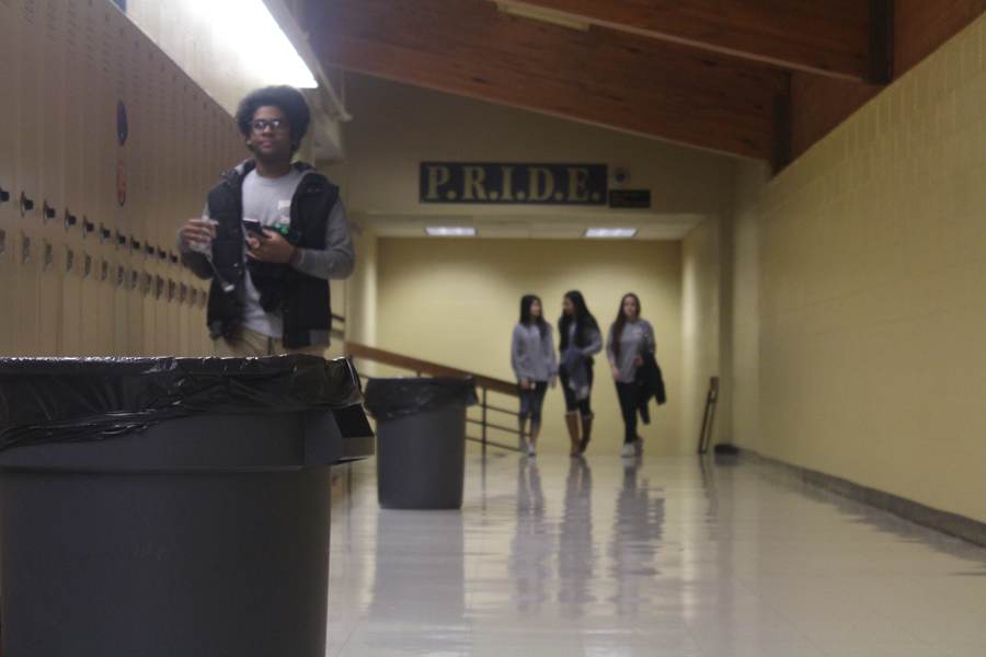 Students pass the trash cans that sit near the butterfly hallway. The hallway is notorious for constantly having trash cans sitting out to catch the water from the leaks. Leaks have been less frequent since the skylights in the butterfly hallway were removed. 