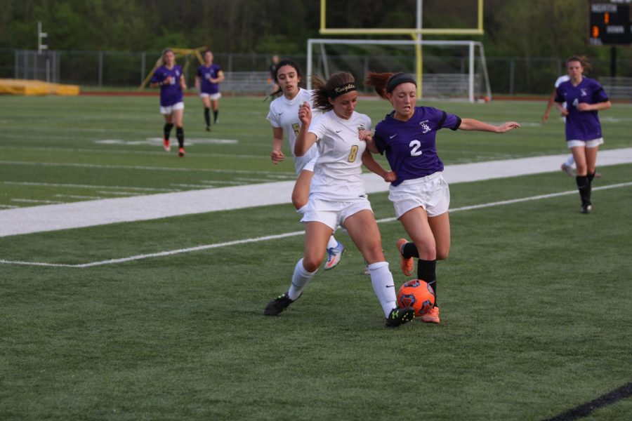 Senior Madelynn Wood challenges a FZW defender on 4/13 in a varsity soccer match at Howell North. 