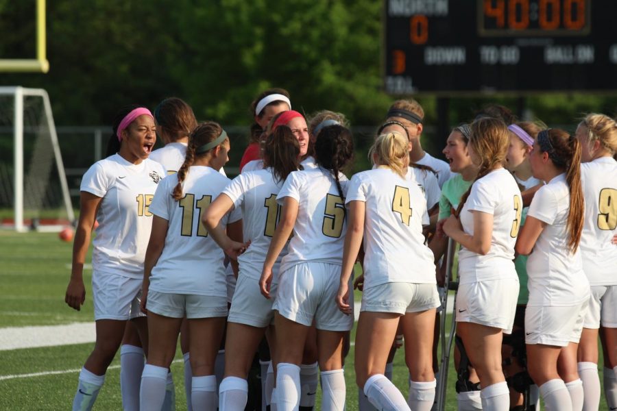 The girls varsity soccer team huddles around the bench on the team's senior night on 5/10.