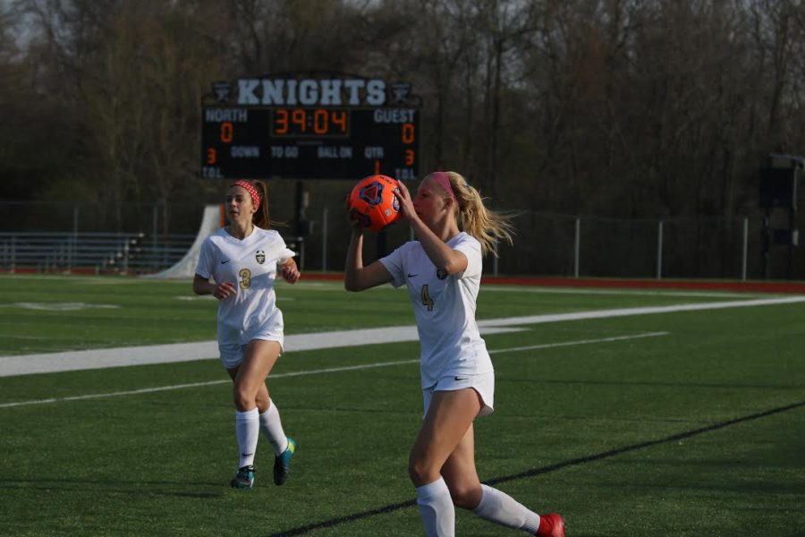 Junior Sam Cary prepares to throw it in with senior Maddy Wood in the background vs. Marquette on 5/3. 