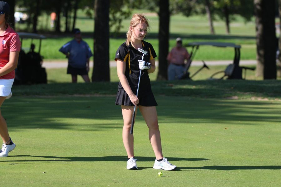 Senior Erika Rogers prepares to put the ball into the hole in a JV tournament 