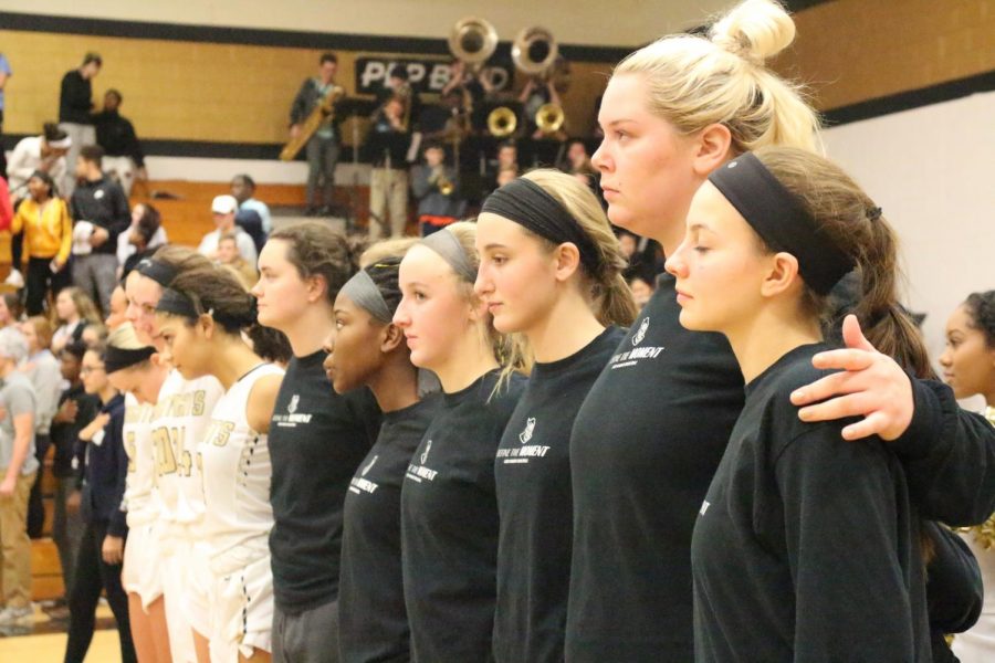 Junior Jenna Thompson (far right) and the girls basketball team stand in line during the National Anthem