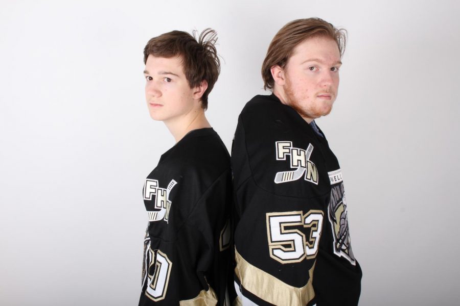 Senior Brett and freshman Matt Wells stand back to back in their hockey jerseys. This is their first year playing on the same team together.