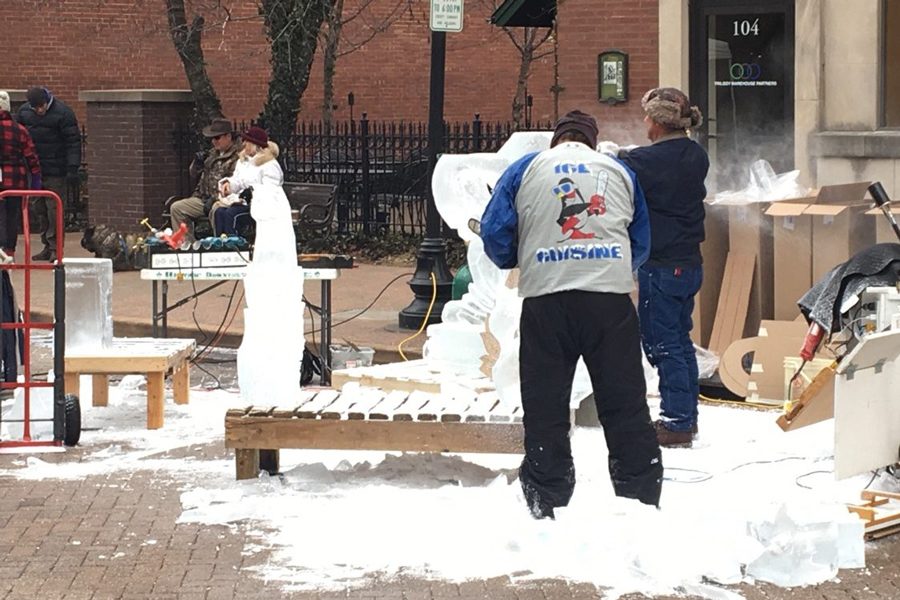 Carvers carefully work to shape the ice into the unique design sculpture to show to the crowd.