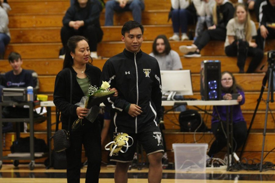 Senior Thadeus Meneses walks with his mother as he Is honored by his team during senior night on 1/15.