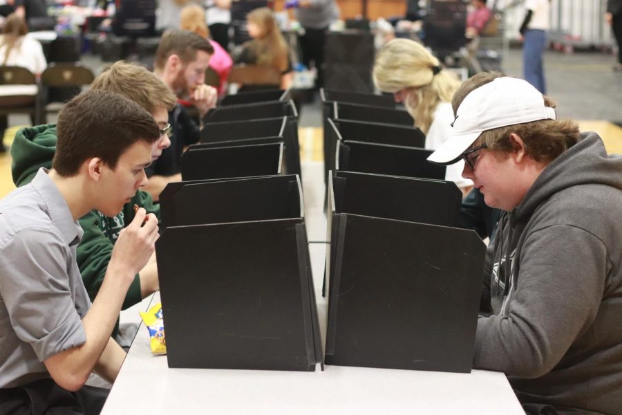 Students and teachers sit along side each other between dividers as they fill out a questionnaire. This is the second station where they answer any questions regarding their family history and health. 