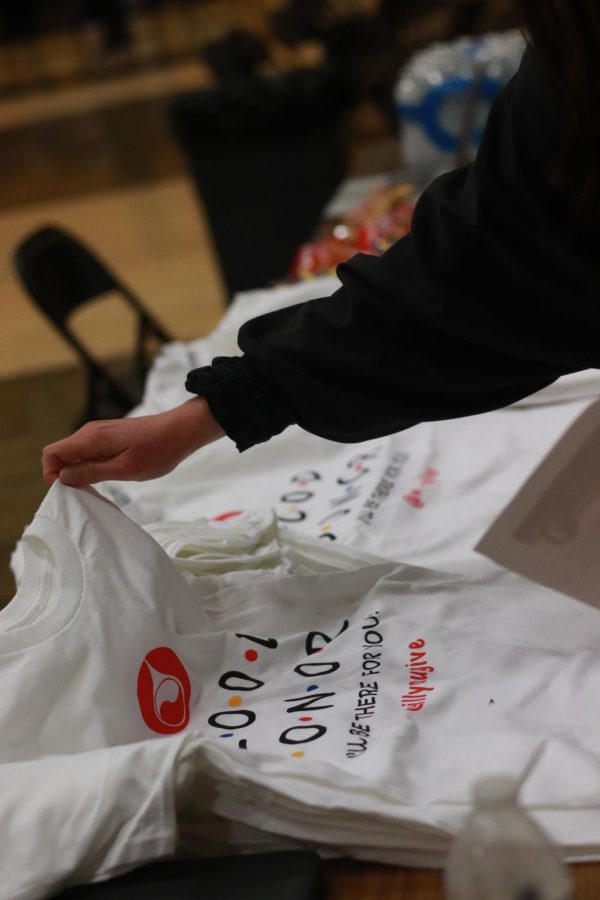 Junior Anjolina Blackwell picks up a T-Shirt after signing into the front desk. Students and teachers are given a complimentary shirt and snack to eat before their blood is drawn. Eating a snack and drinking water before and after giving blood is required as it helps reduce side effects like dizziness and fainting. It also keeps iron and other vitamin levels healthy so students can donate.