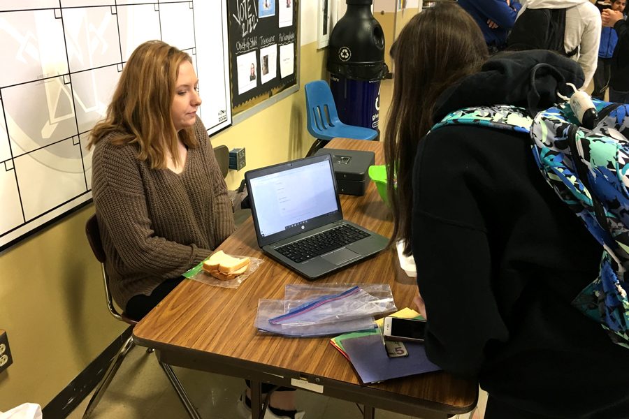 Senior Sarah Moore helps students sign up for the HOSA Dance Marathon on Friday, March 8.