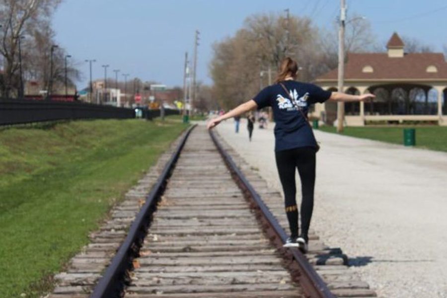 Walking on railroad tracks, junior Isabel Bira holds out her arms to balance herself. Main Street is a common area for people to get food and shop for knick knacks. It is located by the river and has small shops lining the streets.