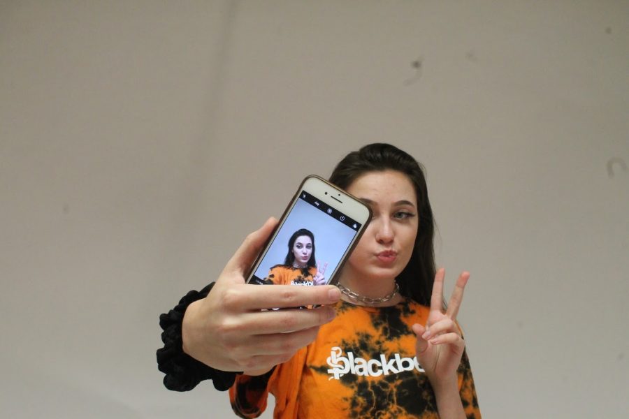 Sophomore Natalie Stevens poses in front of a phone. 