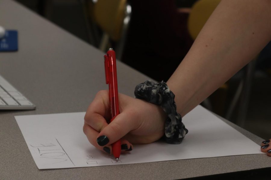 A student checks no on a piece of paper they recieved from a class mate. The school board is going sworn in new members in April. The board only has three available spots. 