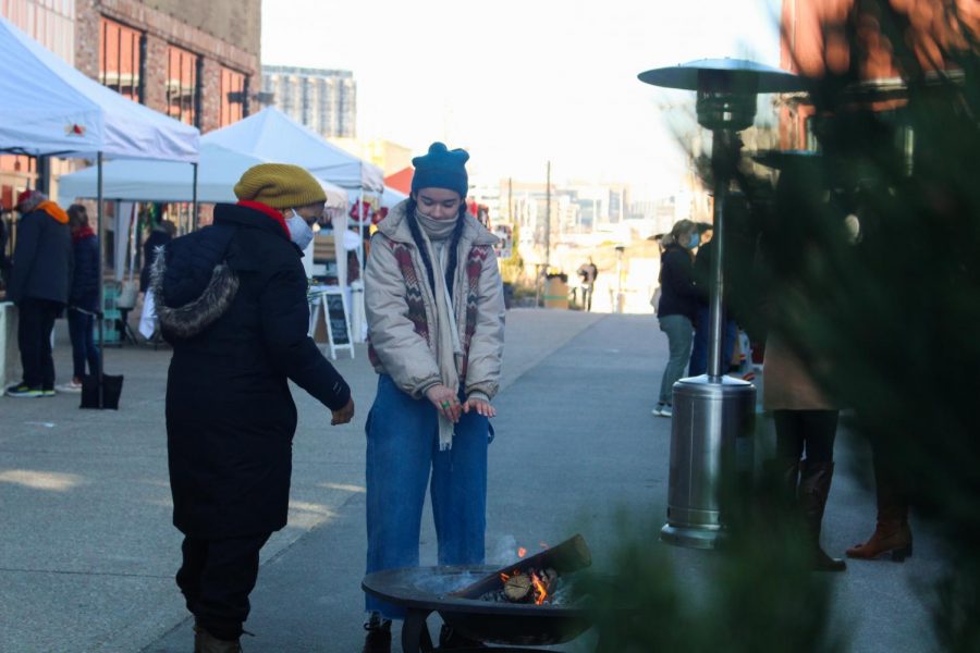 WintrMarkt goers take a break from shopping to warm up by the fire provided by one of the small businesses.